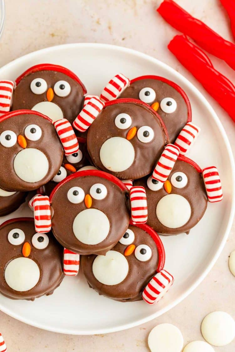 Overhead photo of chocolate covered oreos decorated like penguins on a white plate.