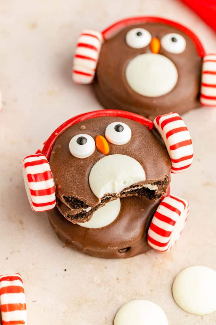 Oreo Penguin cookies on a cream colored surface.