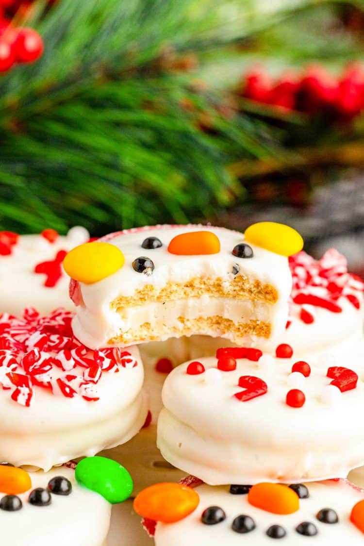 A white chocolate dipped Oreo decorated like a snowman with a bite missing.