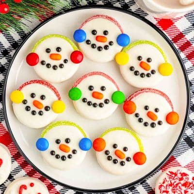 Oreo Snowman Cookies on a white plate on a plaid red and black tablecloth.