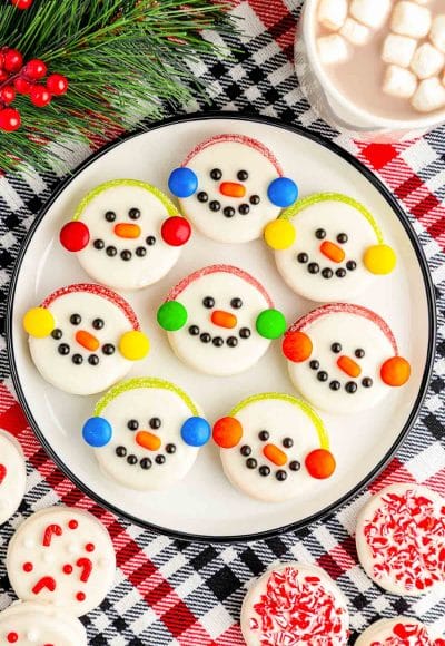 Oreo Snowman Cookies on a white plate on a plaid red and black tablecloth.