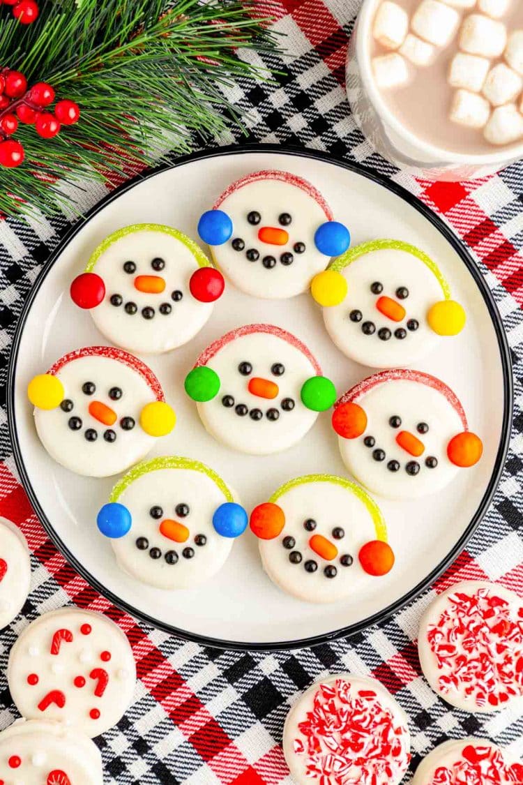 Oreo Snowman Cookies on a white plate on a plaid red and black tablecloth.