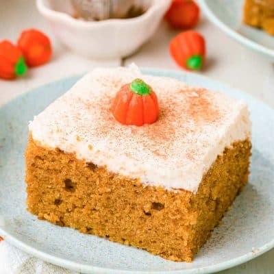 A slice of pumpkin snack cake on a pale blue plate on a white table.