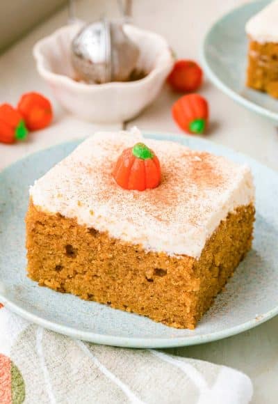 A slice of pumpkin snack cake on a pale blue plate on a white table.