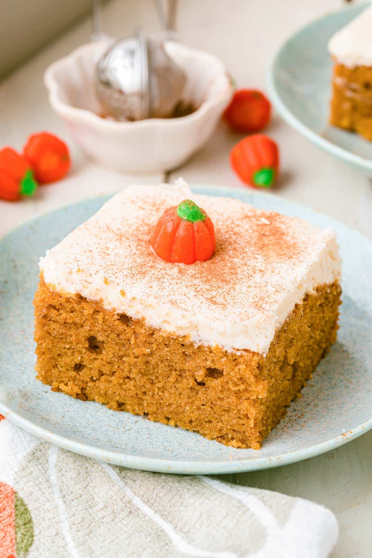 A slice of pumpkin snack cake on a pale blue plate on a white table.