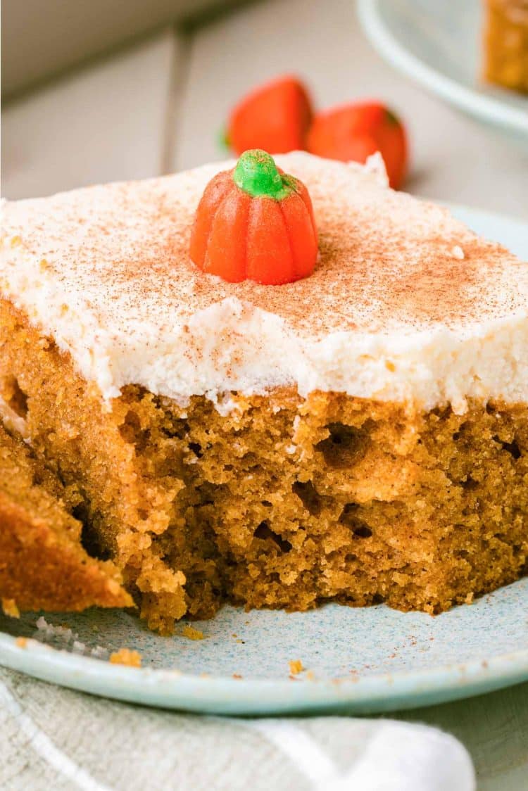 Close up of a slice of pumpkin cake with cream cheese frosting missing a bite.