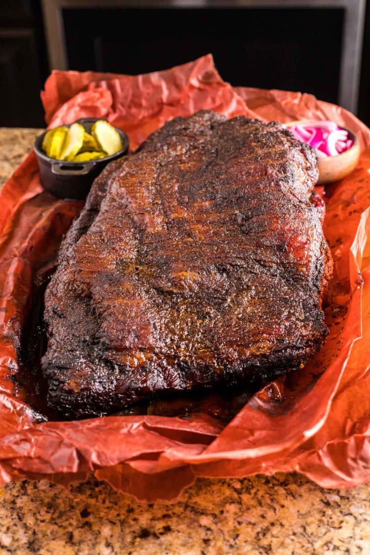 A whole smoked beef brisket on butcher paper on a counter.