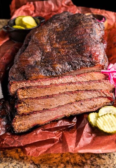 A smoked brisket that's been partially sliced on paper.