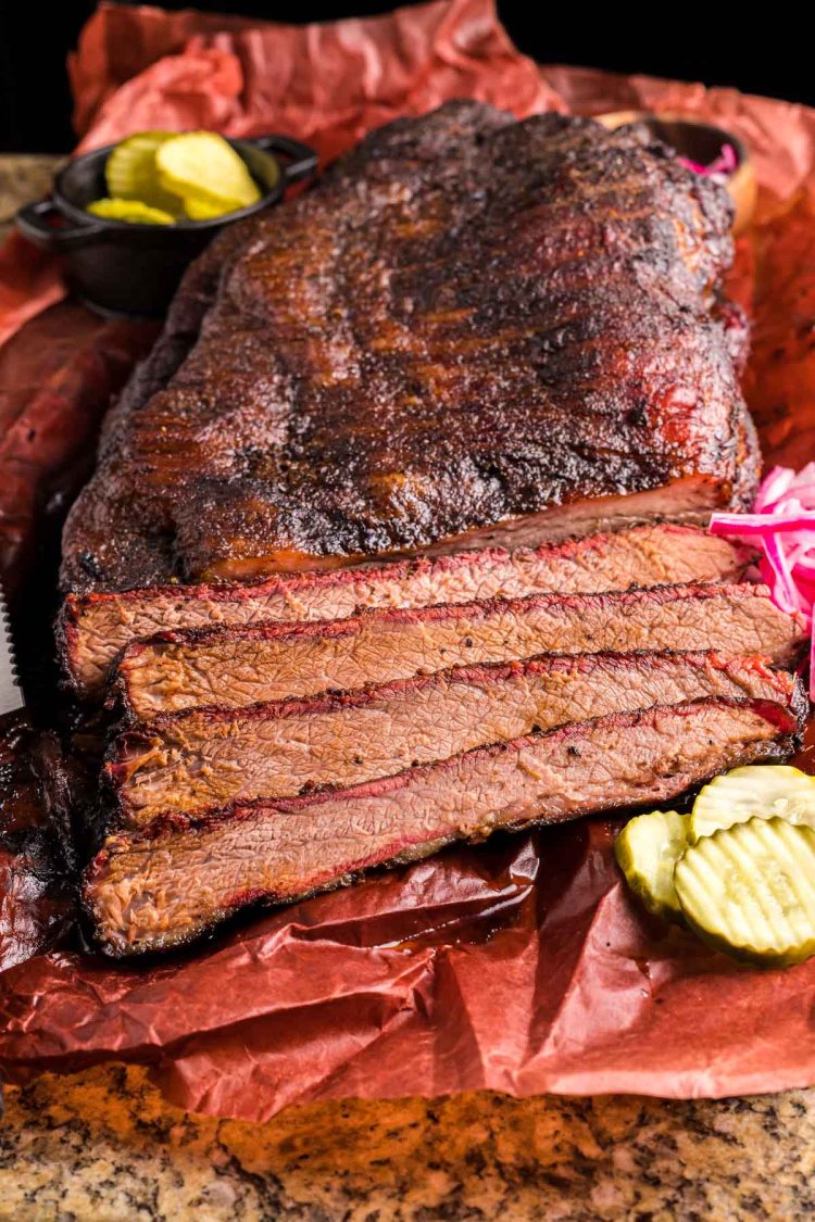 A smoked brisket that's been partially sliced on paper.