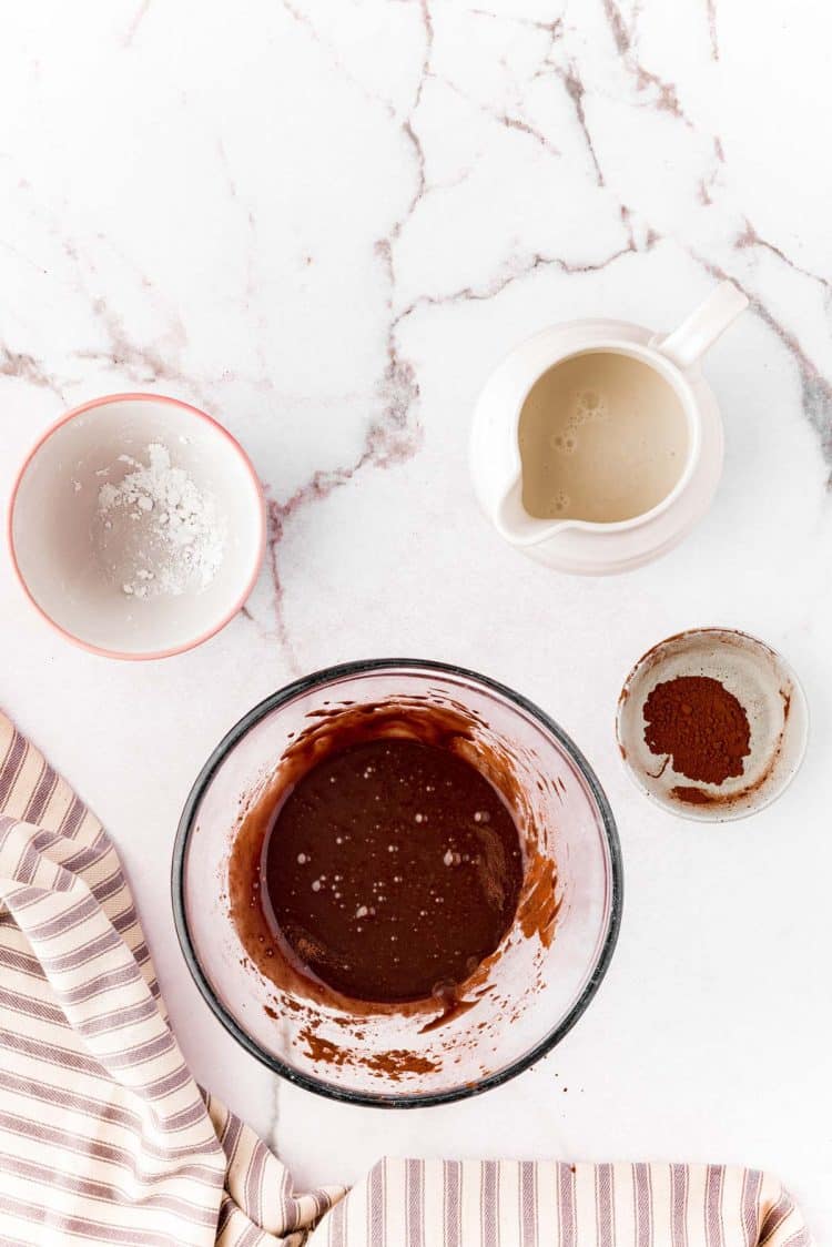 Chocolate glaze for cinnamon rolls prepared in a mixing bowl.