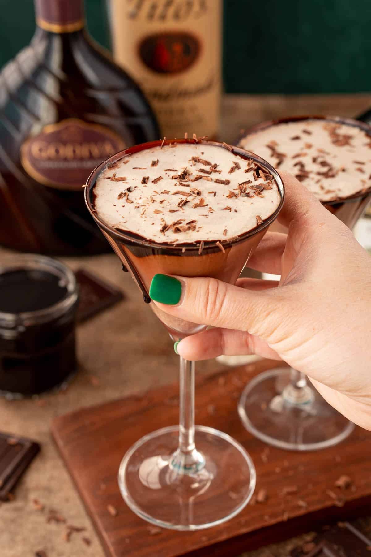 A woman's hand holding a chocolate martini to the camera.