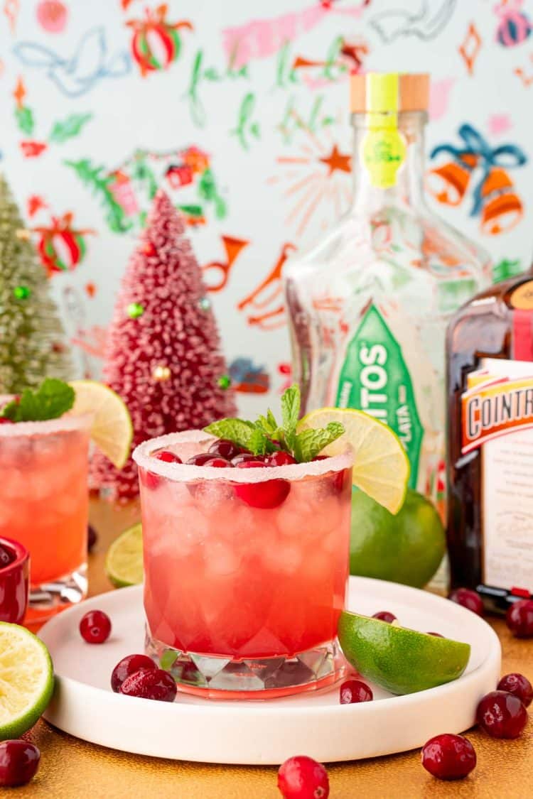 A cranberry margarita on a white tray with holiday decorations around it.