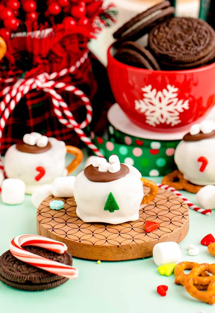 Hot cocoa mug decorated oreo ball on a wooden coaster.