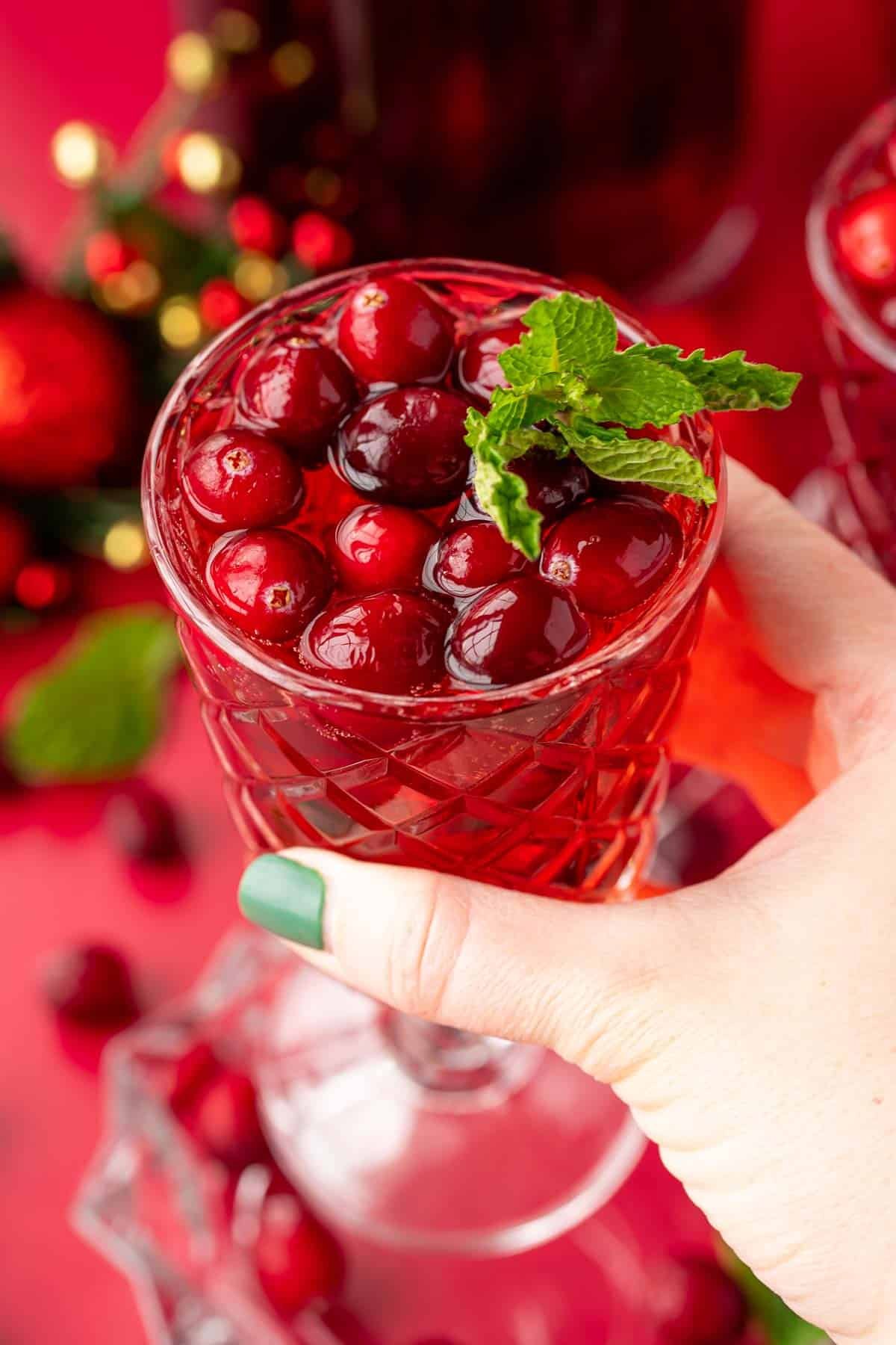 A woman's hand holding a glass of jingle juice to the camera.