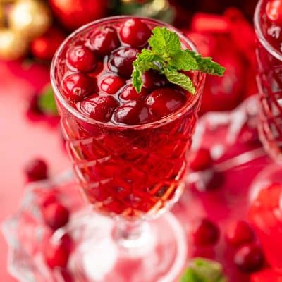 Close up of a glass of jingle juice with cranberries and mint garnish.