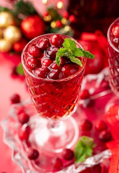 Close up of a glass of jingle juice with cranberries and mint garnish.