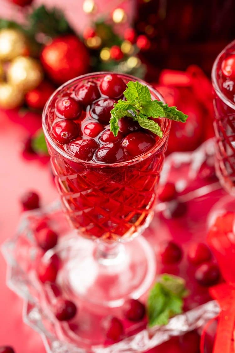 Close up of a glass of jingle juice with cranberries and mint garnish.