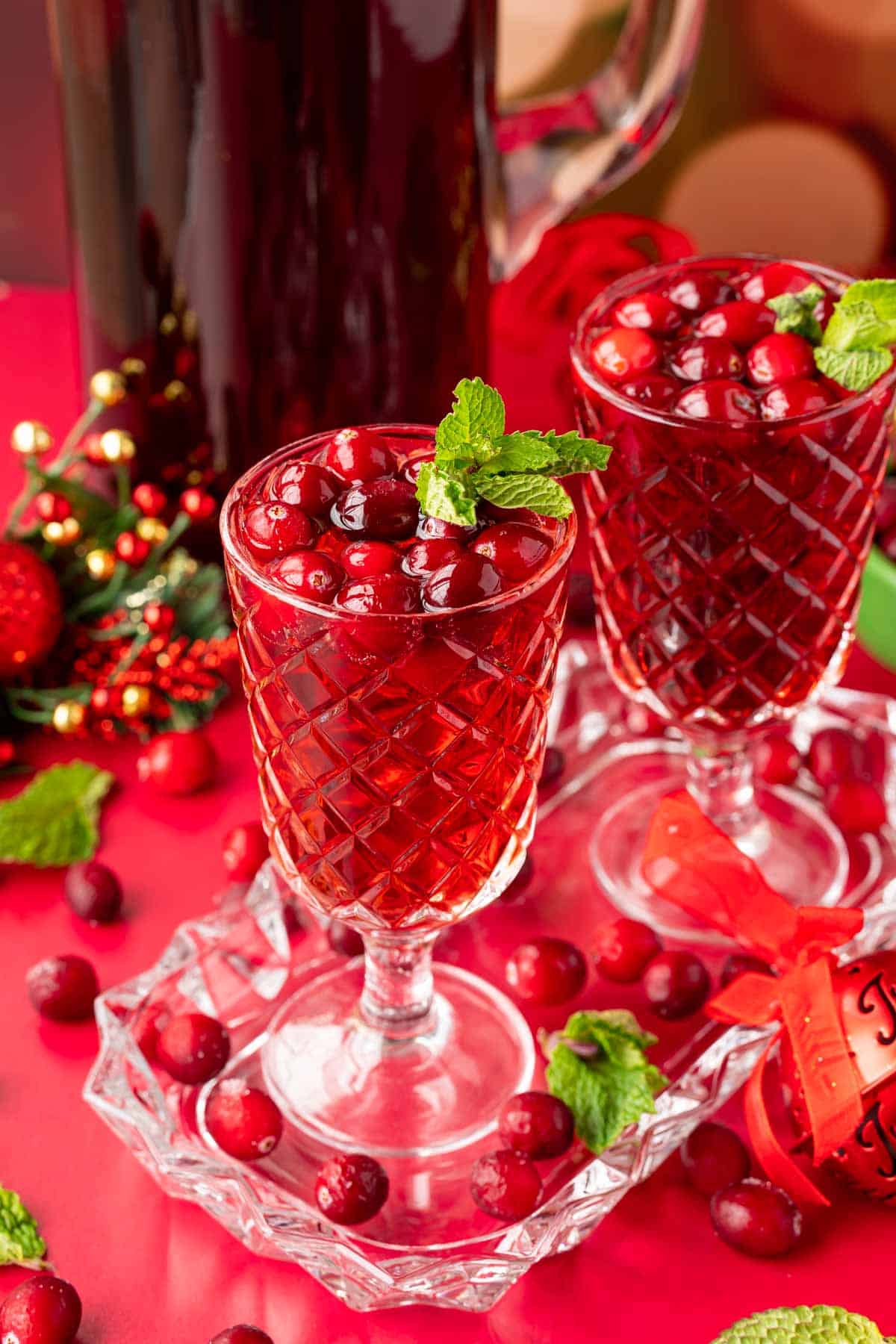 Two glasses of jingle juice on a glass tray with a pitcher behind them.