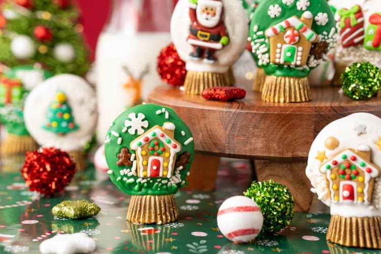 Oreo Snow Globe Cookies on a wooden cake stand.