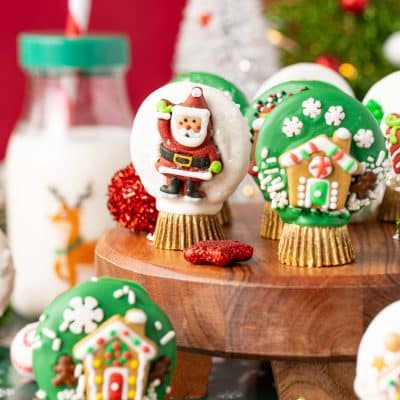 Oreo Snow Globe Cookies on a wooden cake stand.