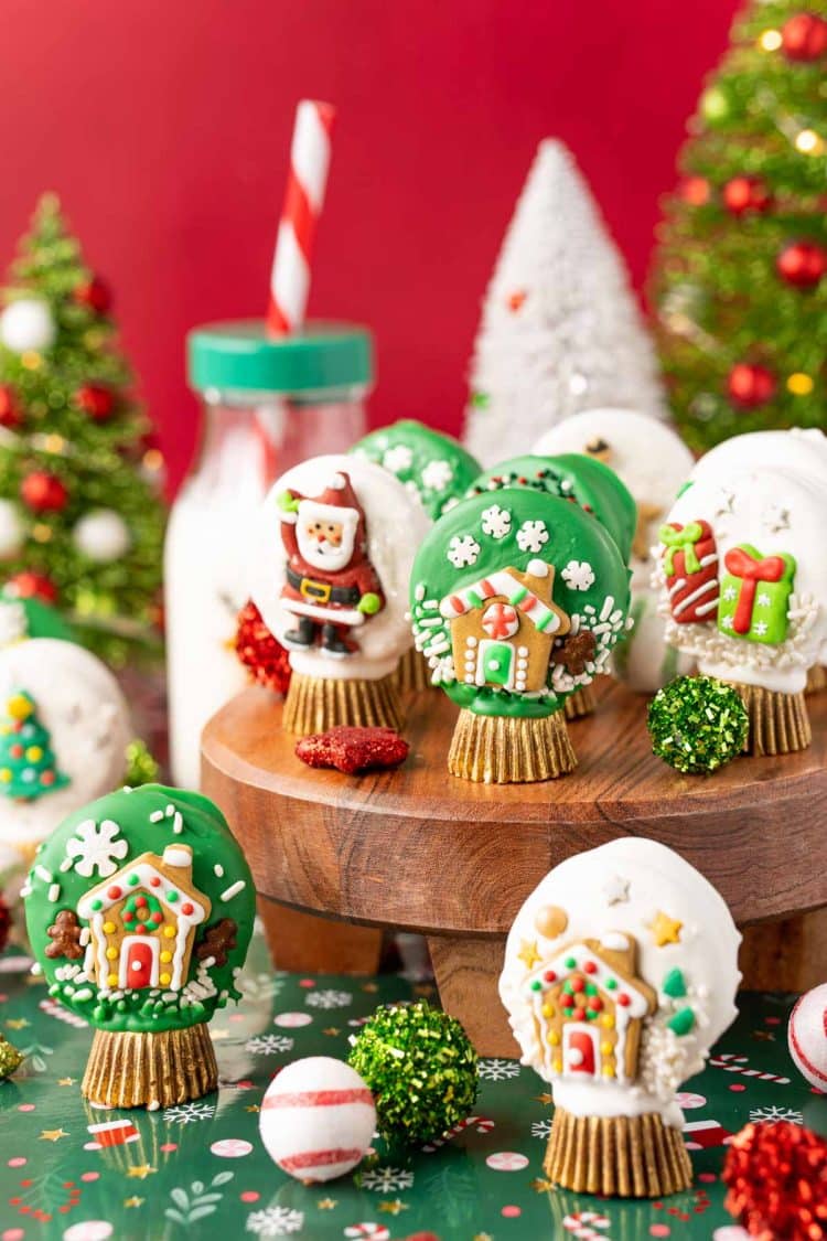 Oreo Snow Globe Cookies on a wooden cake stand.