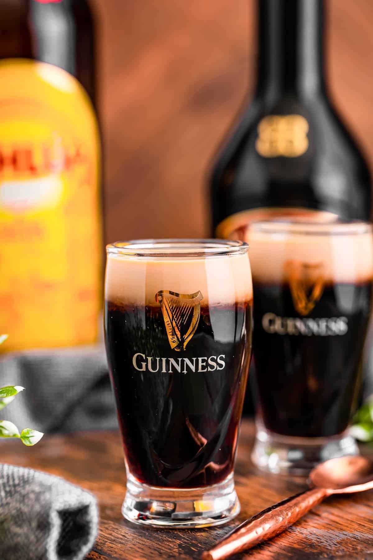 A close up photo of a baby Guinness shot on a wooden board.