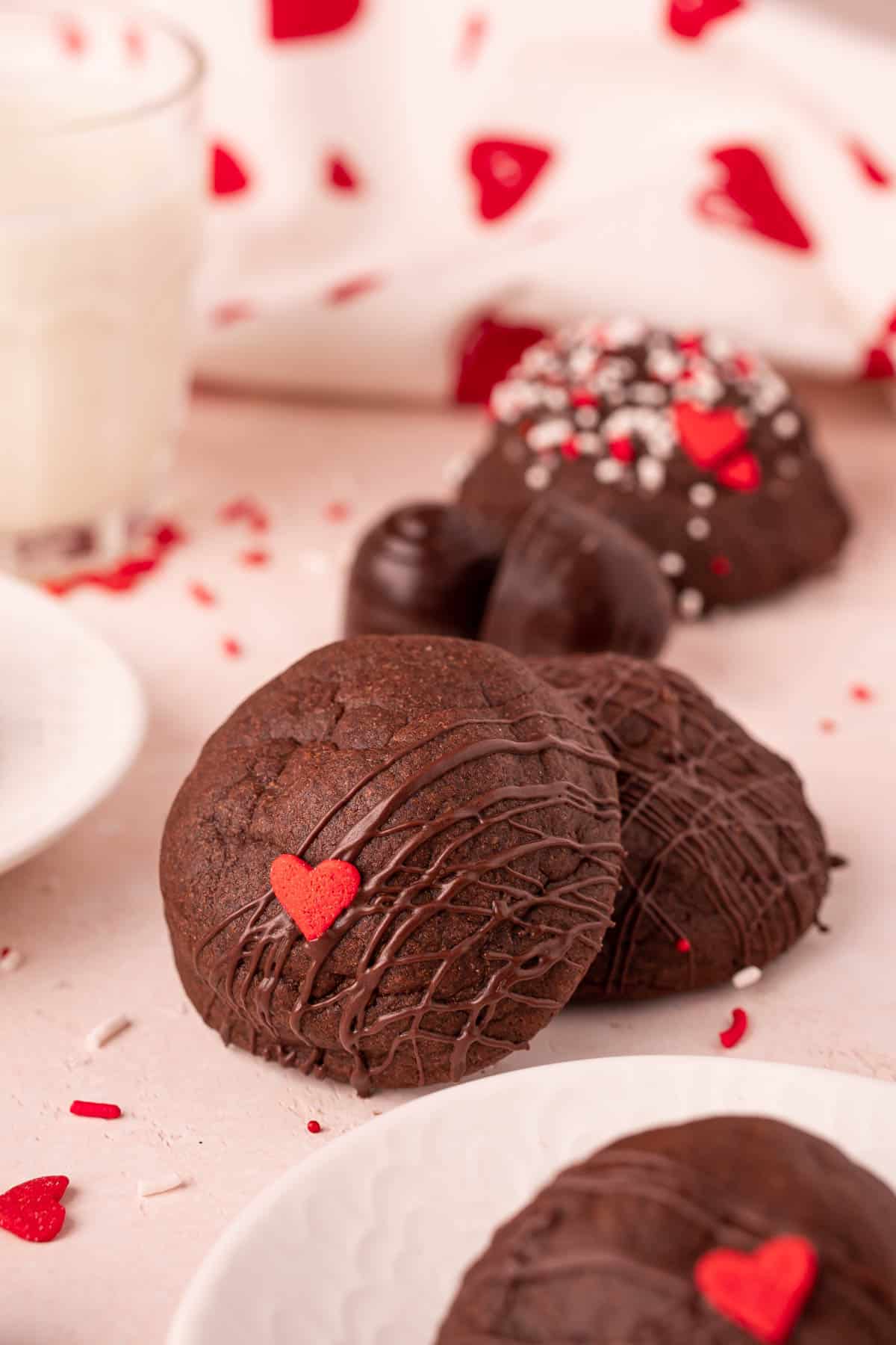 Chocolate cookies that are stuffed with cherry cordials are on a pink surface.