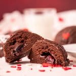 Close up photo of a chocolate cookie cut in half revealing a cherry cordial stuffed inside.