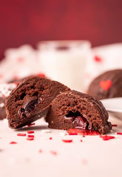 Close up photo of a chocolate cookie cut in half revealing a cherry cordial stuffed inside.