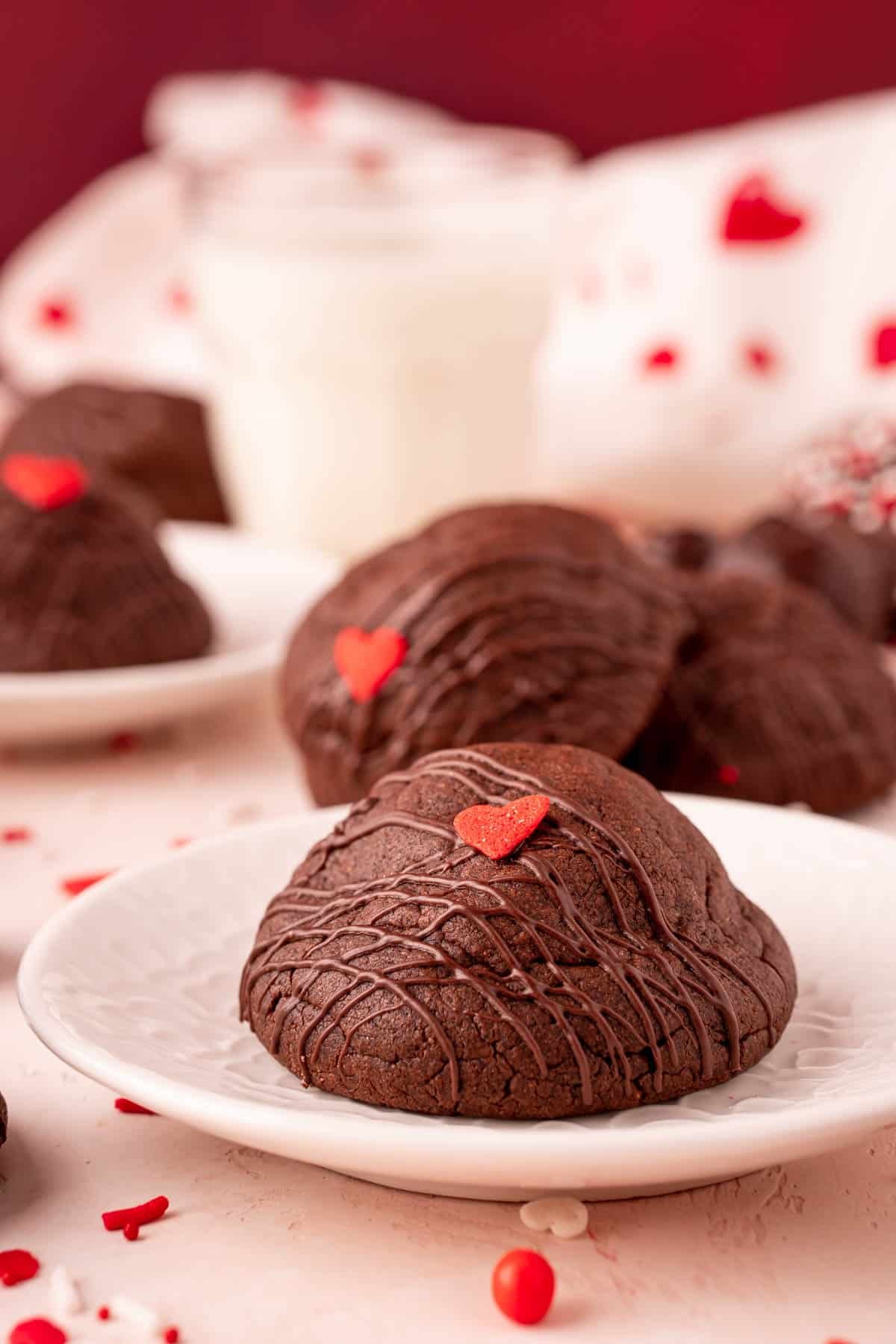 Chocolate cookies on a white plate with more cookies behind it.