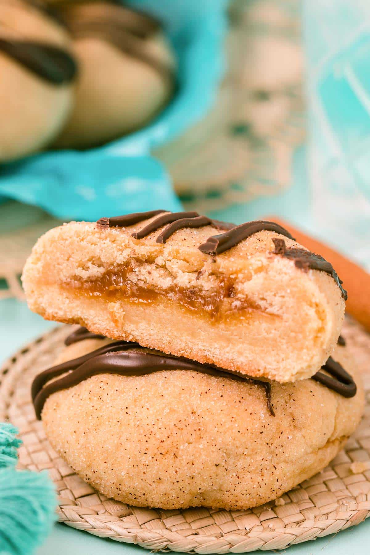 Two cookies stacked, one sliced open revealing the center stuffed with dulce de leche.