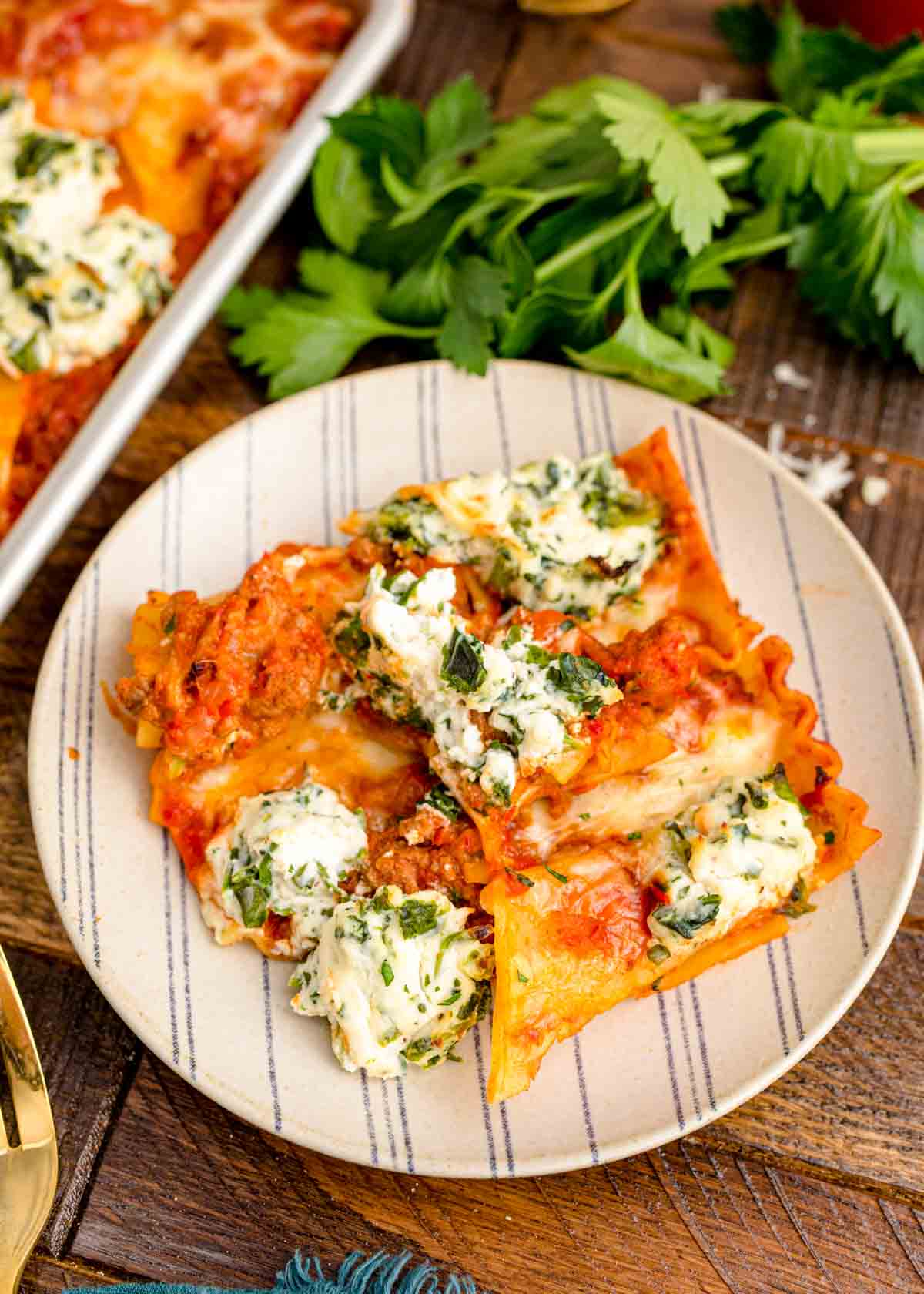 A slice of sheet pan lasagna on a white striped plate.