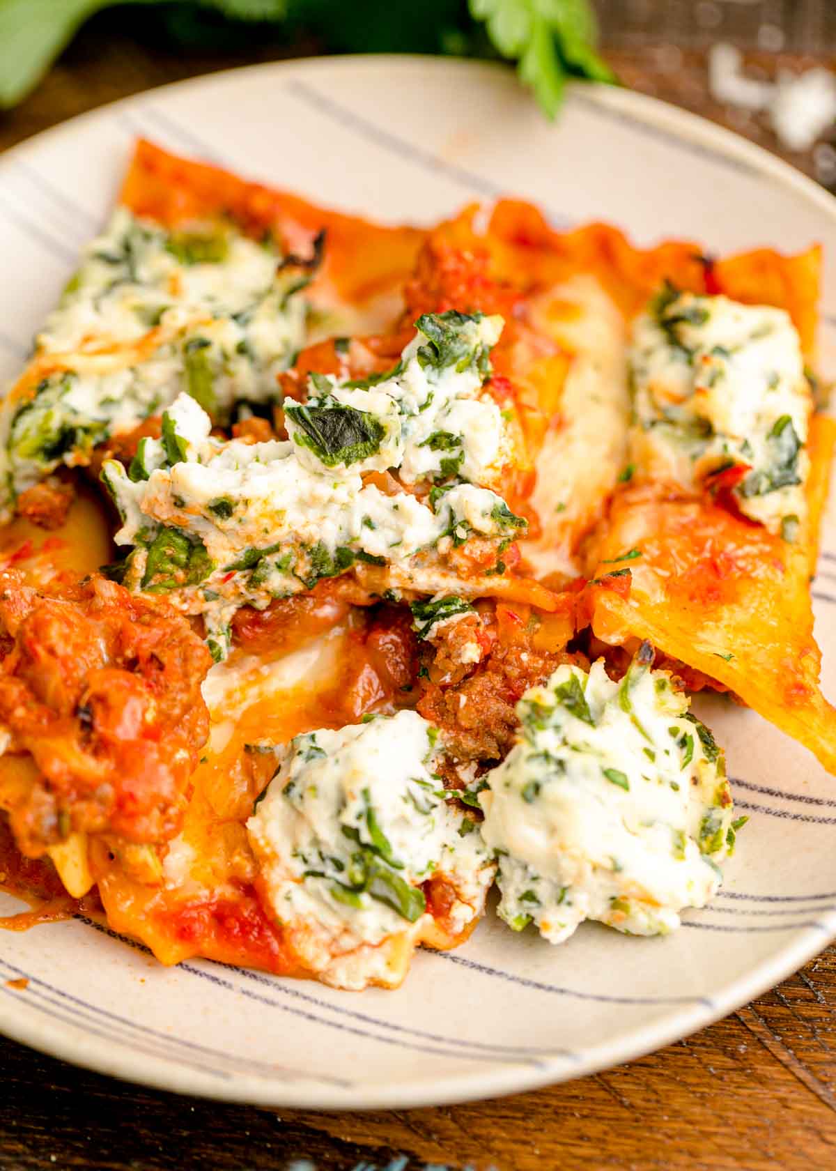 A slice of sheet pan lasagna on a striped plate.