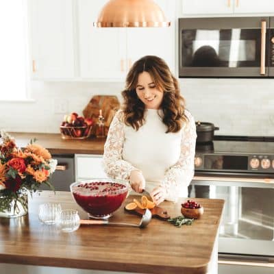 Rebecca Hubbell of Sugar & Soul food blog prepping Christmas Punch at a kitchen island.