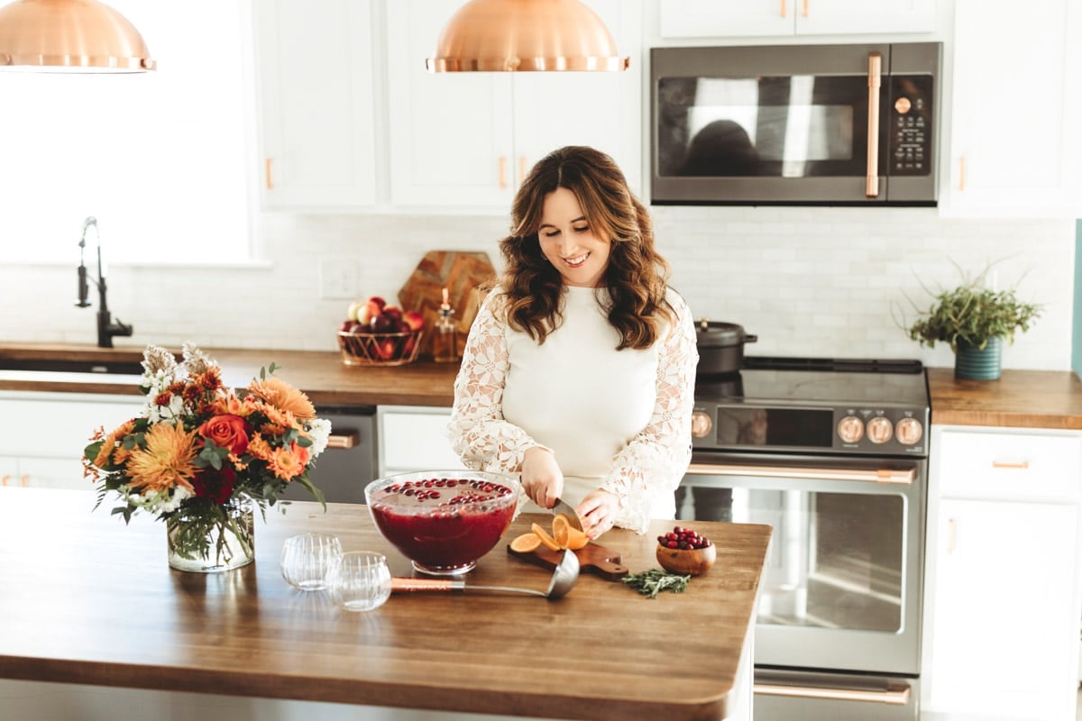 Rebecca Hubbell of Sugar & Soul food blog prepping Christmas Punch at a kitchen island.