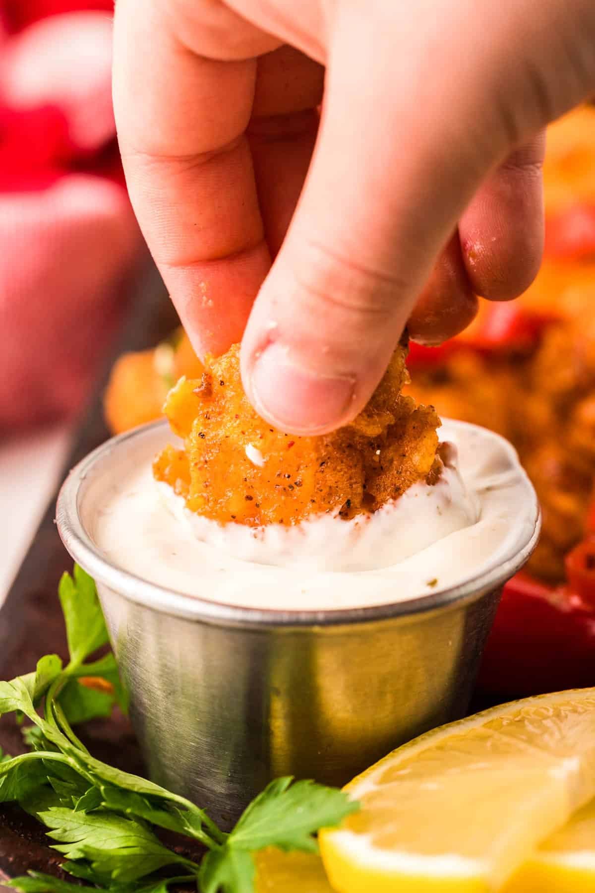 A woman's hand dipping wild west shrimp into ranch dressing.