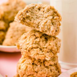 Three cookie butter no bake cookies stacked next to a bottle of milk.