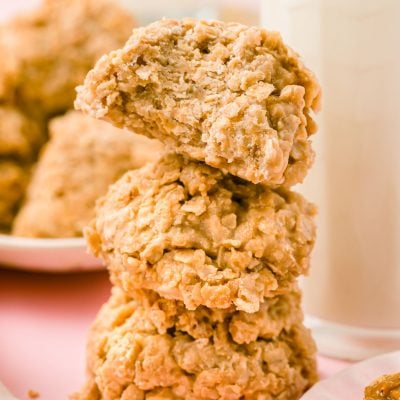 Three cookie butter no bake cookies stacked next to a bottle of milk.