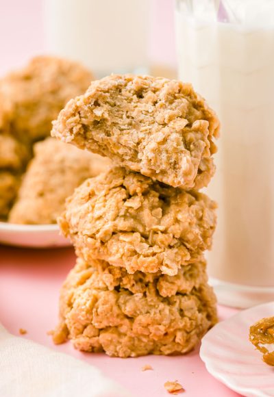 Three cookie butter no bake cookies stacked next to a bottle of milk.