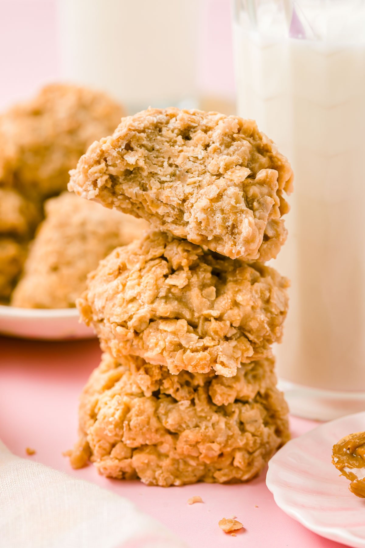 Three cookie butter no bake cookies stacked next to a bottle of milk.