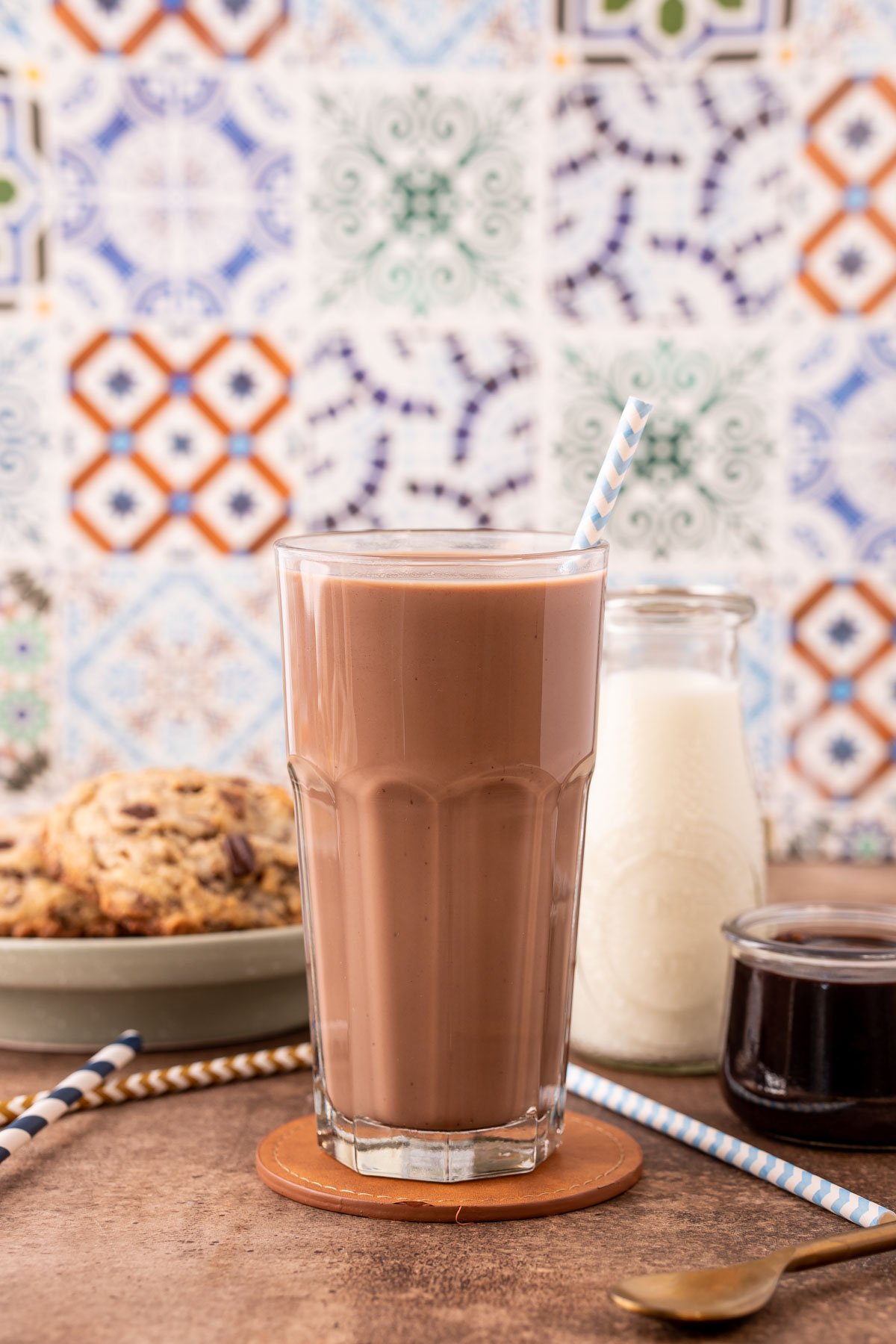 A tall glass of chocolate milk on a brown counter.