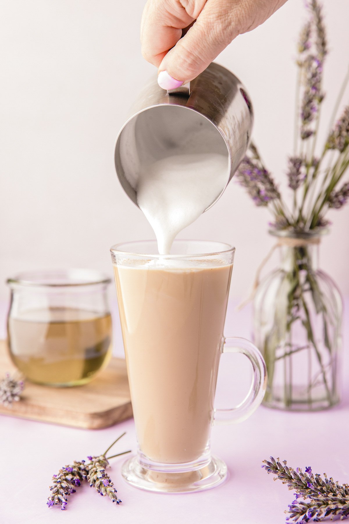 Steamed milk being poured into a mug with espresso and lavender syrup.