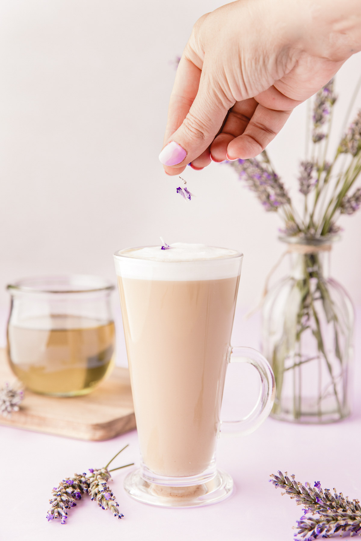 Lavender buds being sprinkled on the top of a lavender latte.