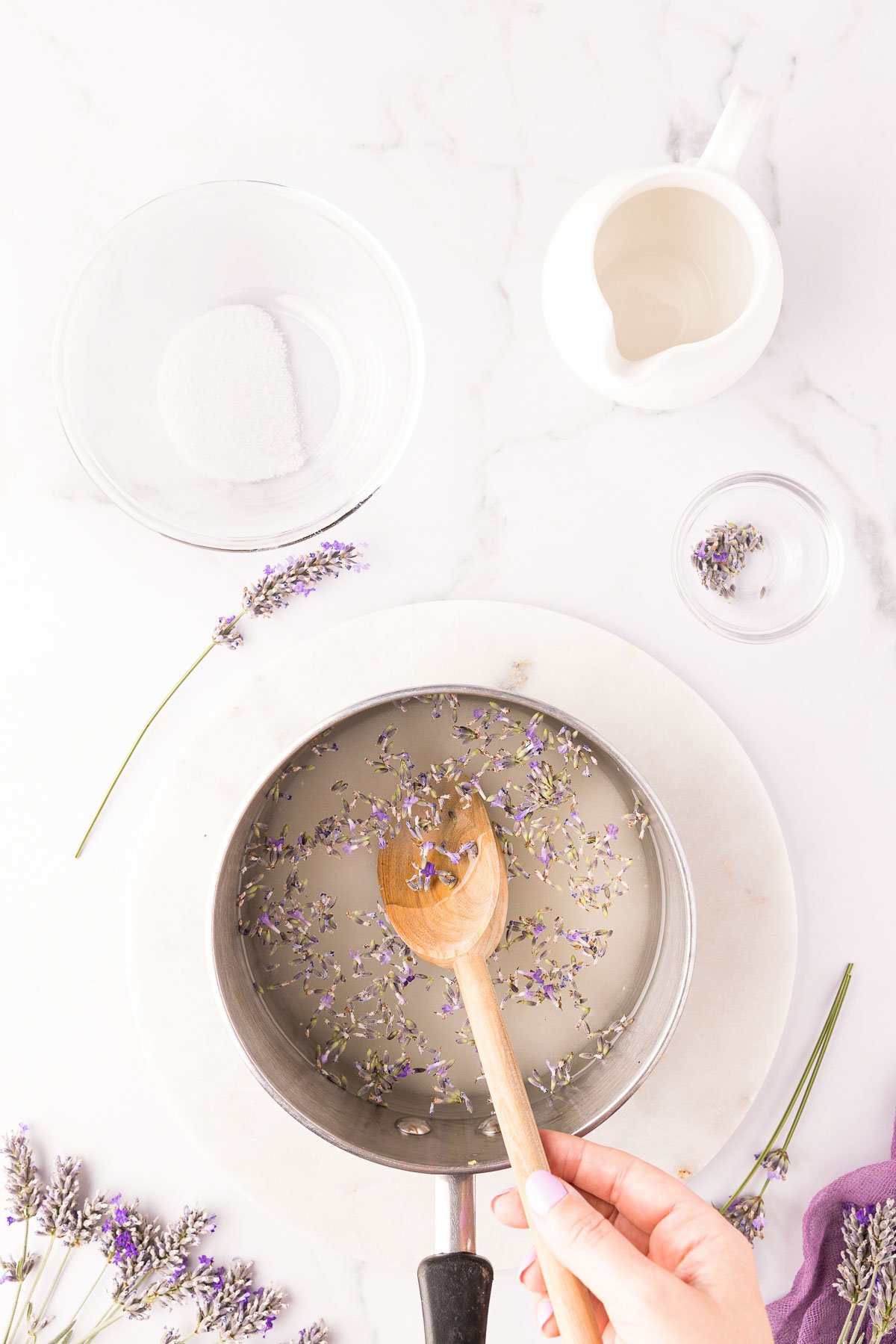 Lavender buds being stirred in a pot with water and sugar to make lavender simple syrup.