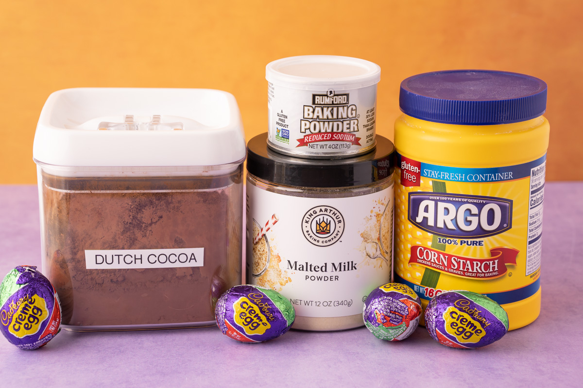 A few ingredients for baking cadbury egg cookies on a purple surface.