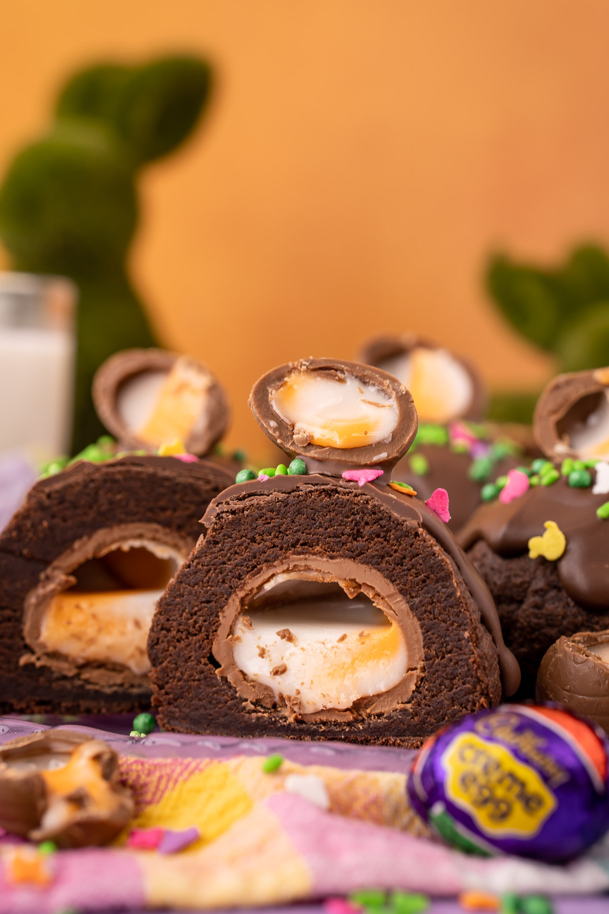 A chocolate cookie stuffed with a Cadbury Creme Egg that's been sliced in half to reveal the inside.