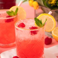 Close up of a raspberry gin daisy on a white marble coasted on a pink table.