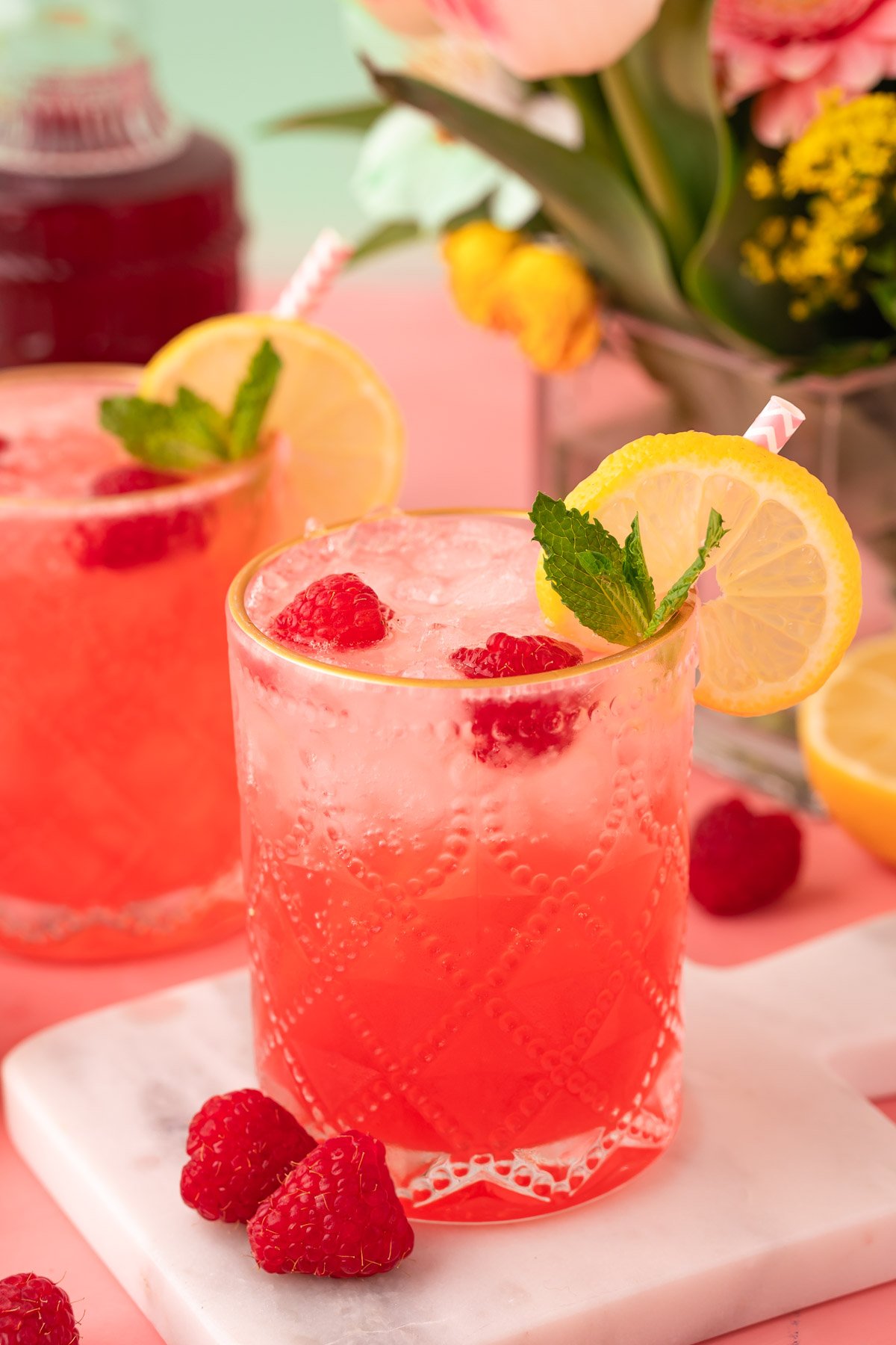 Close up of a raspberry gin daisy on a white marble coasted on a pink table.