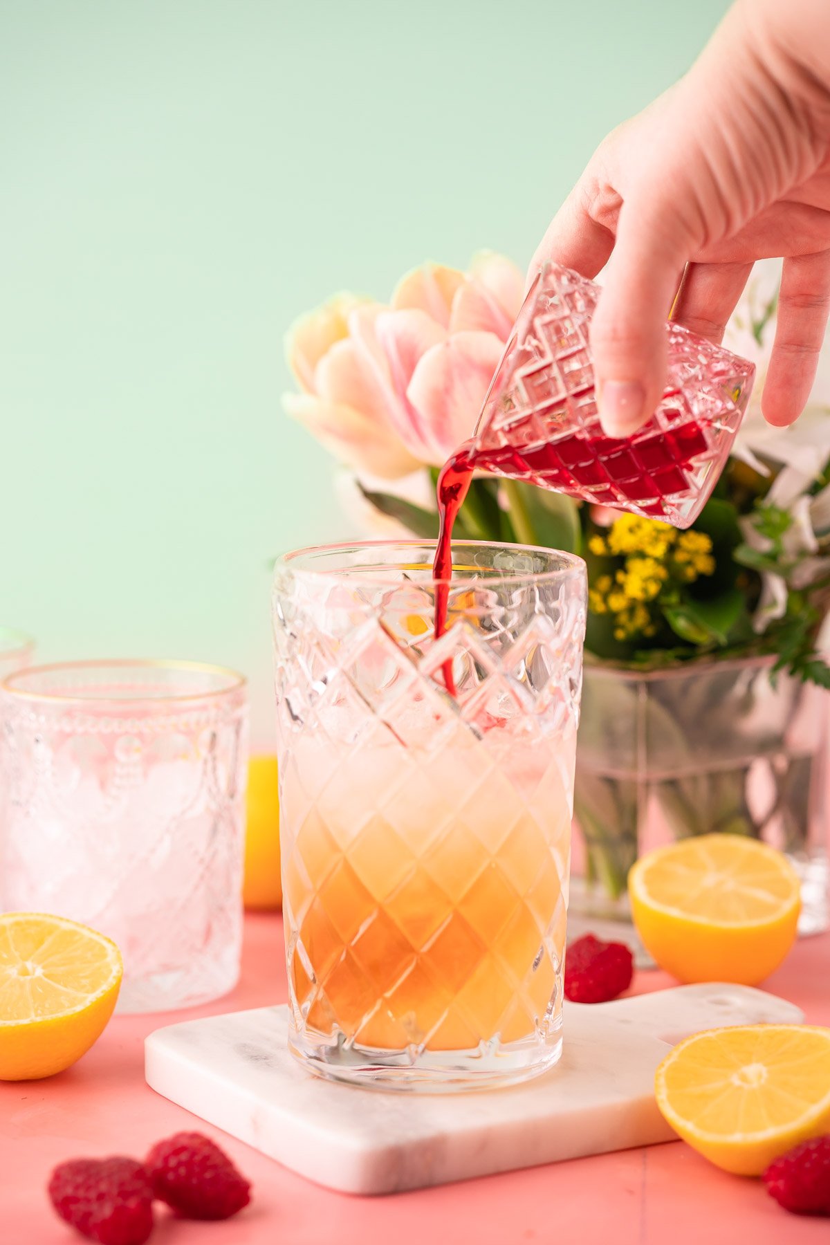 Raspberry Syrup being poured into a cocktail shaker to make a gin daisy.