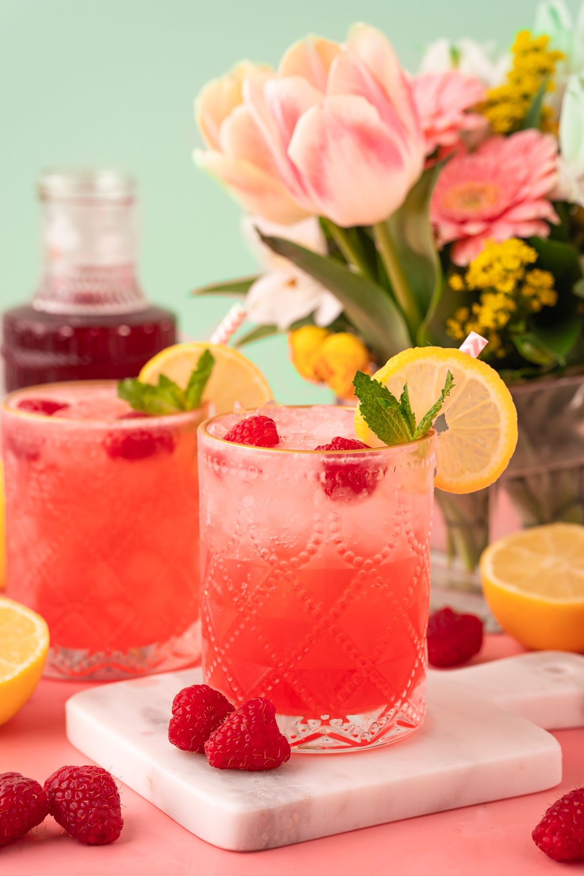 Close up of a raspberry gin daisy on a white marble coasted on a pink table.